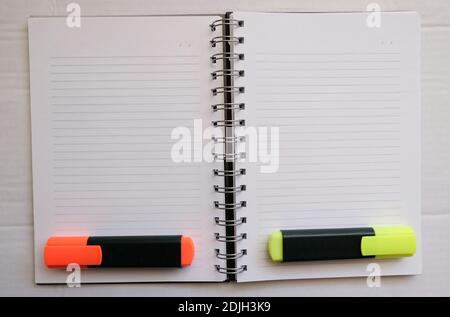 orange and yellow hihglighter on the empty lined notebook. preparation of make a homework.Business work area concept. Stock Photo