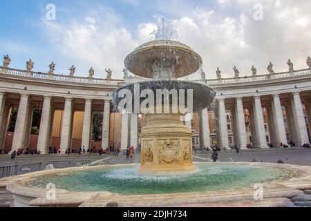 Fontaine del Bernini sur la place Saint-Pierre Vatican . Soleil italien brillant (midi) les gens méconnaissables se reposent (assis) sous la colonnade. Banque D'Images