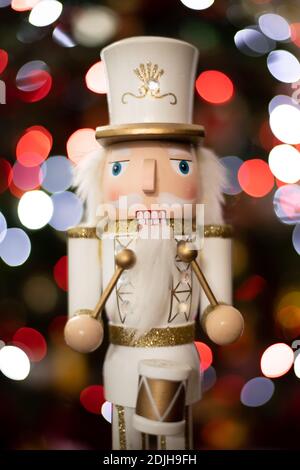 Statuette de casse-noisette de soldat classique avec blanc et or Uniforme et tambour devant l'arbre de Noël flou Banque D'Images