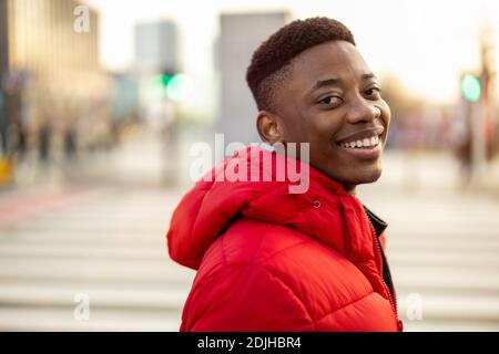 Portrait d'un jeune homme debout dans une rue de ville, souriant Banque D'Images