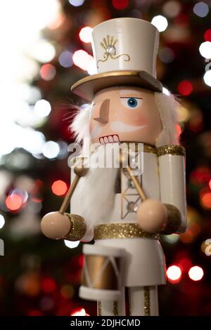 Statuette nutcracker du batteur soldat classique avec uniforme blanc et or et le tambour vu du côté devant un Arbre de Noël Banque D'Images