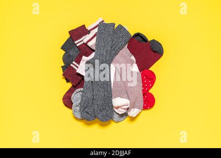 Pile de chaussettes diverses isolées sur fond jaune. Vue de dessus avec chaussettes, tissus et couleurs variés. Banque D'Images