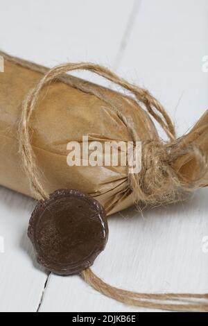 Barre énergétique enveloppée de papier artisanal. Le médaillon de cire d'étanchéité sur une ficelle est visible. Sur les panneaux peints en blanc. Gros plan. Banque D'Images