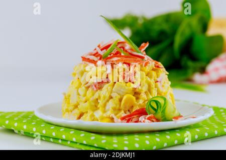 Salade avec bâtonnets de crabe, concombre, œufs sur plaque blanche. Banque D'Images