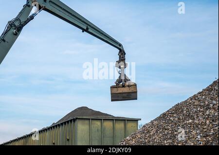 Grande pelle hydraulique manipulant des cailloux de la pile de pierres au conteneur. Machine en chantier. Industrie. Banque D'Images