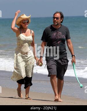 Rosanna Arquette fait une promenade sur la plage avec un ami tout en jouant à FETCH avec quelques chiens. Peut-être l'actrice est-elle consciente de la portée, car elle semble être en fourre-tout un pot de yogourt rempli de sable. Malibu, Calif. 7/9/06 Banque D'Images