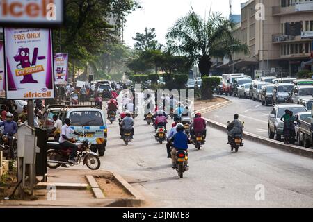 Les Ougandais voyageant d'une destination à l'autre en boda (taxis à moto) sur une large avenue de la capitale. Banque D'Images