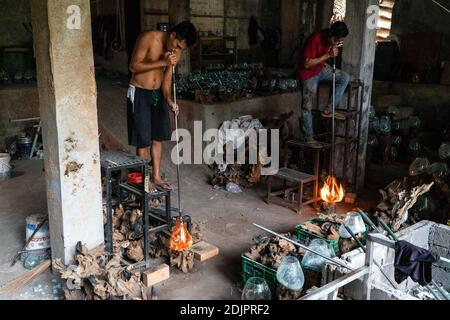 TEGALALANG/BALI-4 DEC 2020: A glazier is shaping hot glass which is done by blowing. Glass crafts in Ubud Bali became a favorite during the COVID-19 p Stock Photo