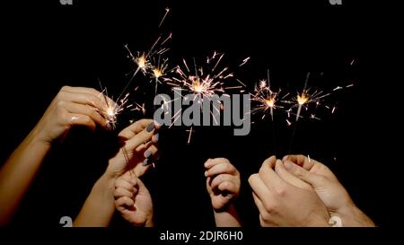 Gros plan des mains ou des paumes tenant et agitant les spameurs brûlants devant un arrière-plan noir foncé. Des lumières étincelantes pour les fêtes d'anniversaire, les mariages, le nouvel an, la veille de Noël, Noël. 6k de mise à niveau vers le bas. Feu Bengale Banque D'Images