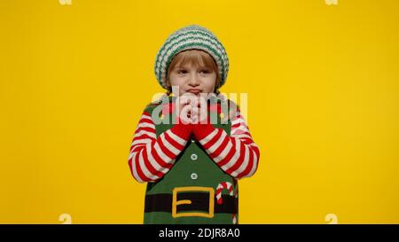 Sly kid teen girl steepls fingers and schemes something gets interesting idea how to decorate house, waiting for gift box. New Year and Christmas holidays winter time. Child Christmas elf Santa helper Stock Photo