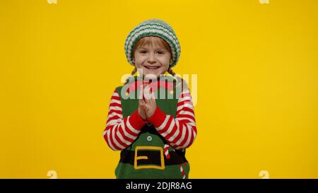 Sly kid teen girl steepls fingers and schemes something gets interesting idea how to decorate house, waiting for gift box. New Year and Christmas holidays winter time. Child Christmas elf Santa helper Stock Photo