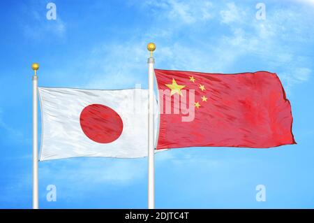 Japon et Chine deux drapeaux sur les mâts de drapeaux et bleu nuageux ciel Banque D'Images