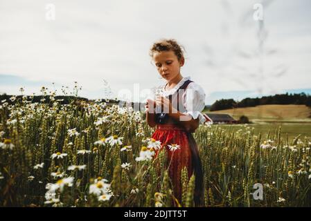 Belle fille collectant des daises sur le terrain en Norvège portant une robe Banque D'Images