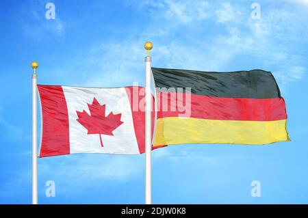 Canada and Germany two flags on flagpoles and blue cloudy sky Stock Photo