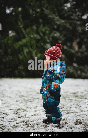 Profil de jeune enfant adorable debout au parc sur neige jour à winte Banque D'Images