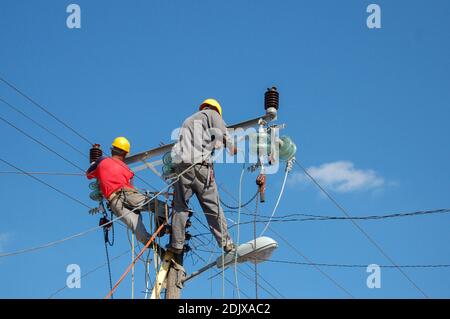 A low angle shot of electric linemen working on pole Stock Photo