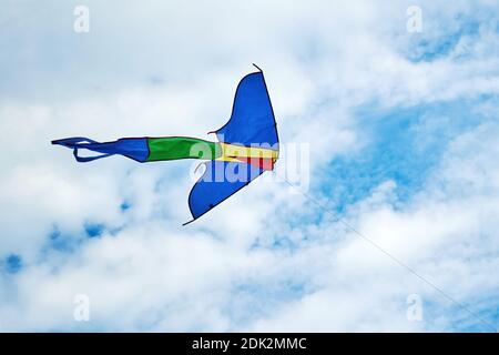 Grand cerf-volant coloré dans le ciel bleu avec des nuages blancs. Jouets et jeux pour enfants. Activités de loisirs en plein air Banque D'Images