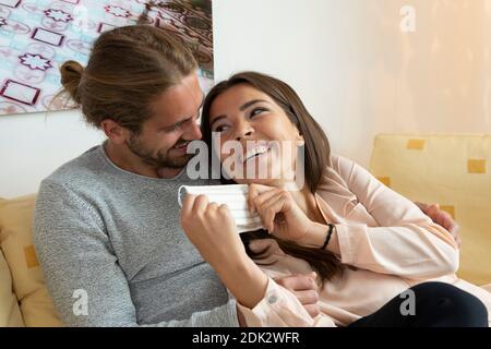 jeune couple avec masque de bouche et de nez sur le canapé Banque D'Images