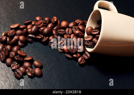 Photo teintée de grains de café saupoudrée de la tasse blanche. Nourriture et boissons pour la publicité des cafés et des restaurants Banque D'Images