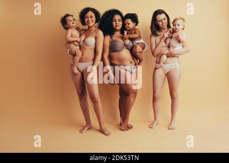 Les femmes avec des corps post-partum portant leurs enfants. Groupe complet de mères avec bébés. Banque D'Images