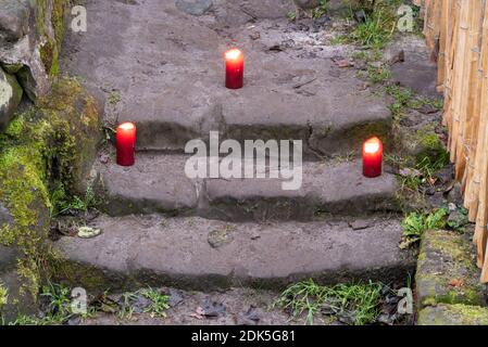 13 décembre 2020, Saxe-Anhalt, Langenstein : trois bougies rouges brûlent devant l'entrée d'une grotte. A Langenstein, dans les montagnes Harz, vous attendez littéralement qu'un tuyau Hobbit vienne au coin de la rue. Dans la petite ville près de Halberstadt, il y a encore une douzaine d'habitations troglodytiques bien conservées, qui nous rappellent la plaine d'inondation des deux BEST-sellers 'le Seigneur des anneaux' et 'le Hobbit' de l'écrivain J.R.R. Tolkien. Les habitations ont été sculptées dans plusieurs roches de grès avec un marteau et un burin par des familles paysannes à partir de 1855. Aujourd'hui, une association prend soin Banque D'Images