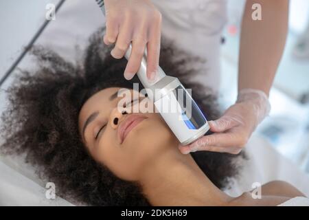 Fille pendant la procédure cosmétique de matériel facial Banque D'Images