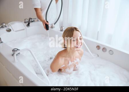 Une femme souriante et heureuse se reposant dans l'eau avec de la mousse Banque D'Images