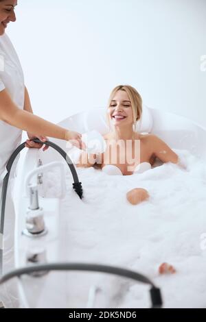 Une femme souriante et heureuse, au spa, allongé dans le bain avec de la mousse resort Banque D'Images