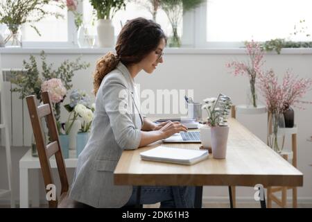 Concentrated female small business owner using laptop at work desk Stock Photo