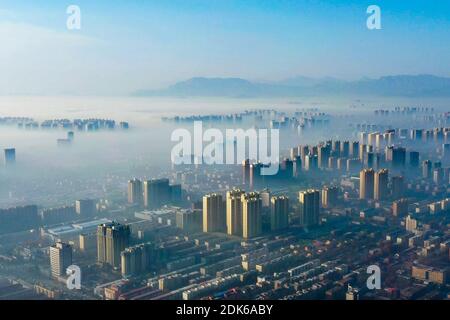 Les nuages d'advection s'écoulent lentement entre les bâtiments urbains, se profilant comme un parc d'expositions dans la ville de Shijiazhuang, province du Hebei au nord de la Chine, 12 décembre Banque D'Images