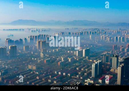 Les nuages d'advection s'écoulent lentement entre les bâtiments urbains, se profilant comme un parc d'expositions dans la ville de Shijiazhuang, province du Hebei au nord de la Chine, 12 décembre Banque D'Images