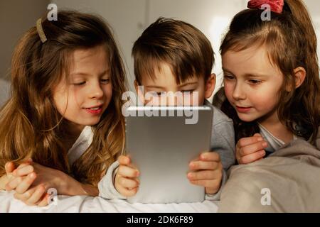 Les enfants au lit à l'aide d'une tablette numérique Banque D'Images