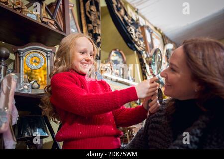 Amuse-toi bien. Famille, mère et enfant joyeux à la recherche de décoration et de cadeaux de vacances dans le magasin de la maison. Des articles rétro et élégants pour des voeux ou un design. Rénovation intérieure, célébration du temps. Banque D'Images