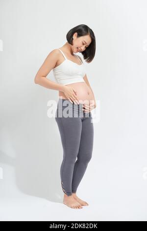 Femme enceinte en caressant son ventre sur fond blanc Banque D'Images