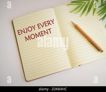 Conceptual hand writing showing Enjoy Every Moment. Business photo text being pleased with your life .Enjoy every moment text written in notebook Stock Photo