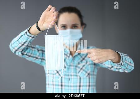 La femme en masque médical de protection tient un masque médical dans ses mains Banque D'Images