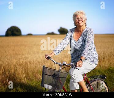 Femme plus âgée en vélo et souriant Banque D'Images