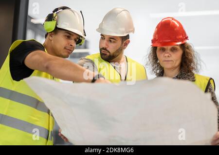 Les travailleurs qui examinent le plan directeur sur le chantier de construction Banque D'Images