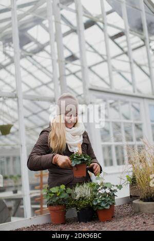 Femme souriante regardant des fleurs devant la serre Banque D'Images
