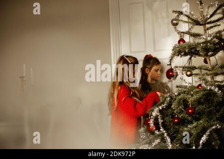 Girls decorating Christmas Tree Banque D'Images