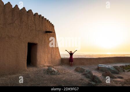 Voyageur féminin explorant le fort de Dhayah au nord de Ras Al Khaimah, aux Émirats arabes Unis, au coucher du soleil Banque D'Images