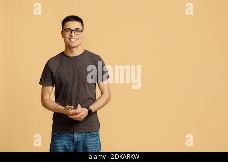 Concept de personnes, de jeunes, d'émotions. Souriant attrayant jeune étudiant blogueur gars en lunettes regarde la caméra Banque D'Images