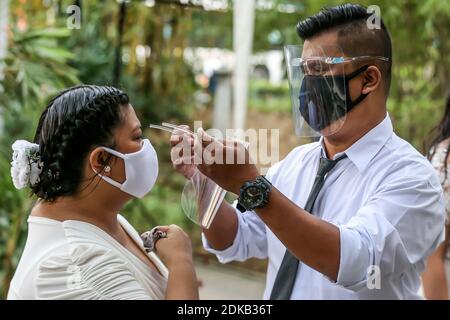 Makati, Philippines. 15 décembre 2020. Un marié fixe le bouclier facial de sa mariée lors d'un mariage caché dans un parc de Makati City, aux Philippines, le 15 décembre 2020. Le gouvernement philippin a imposé une politique plus stricte sur la couverture faciale en raison des inquiétudes d'une éventuelle augmentation des cas pendant la période des fêtes. Crédit: Rouelle Umali/Xinhua/Alamy Live News Banque D'Images