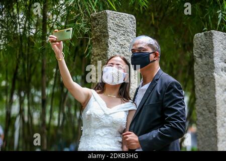 Makati, Philippines. 15 décembre 2020. Un couple portant des masques prend un selfie lors d'un "mariage masqué de cul" dans un parc de la ville de Makati, aux Philippines, le 15 décembre 2020. Le gouvernement philippin a imposé une politique plus stricte sur la couverture faciale en raison des inquiétudes d'une éventuelle augmentation des cas pendant la période des fêtes. Crédit: Rouelle Umali/Xinhua/Alamy Live News Banque D'Images