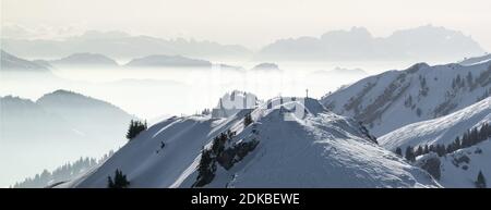 Panorama des montagnes enneigées dans le brouillard de la vallée d'inversion de basse altitude. Silhouettes des montagnes brumeuses. Paysage hivernal pittoresque et enneigé. Vue de SStuiben à Saentis Banque D'Images