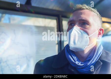 Man se tient à l'arrêt de bus qui attend le bus dans un masque antiviral Banque D'Images