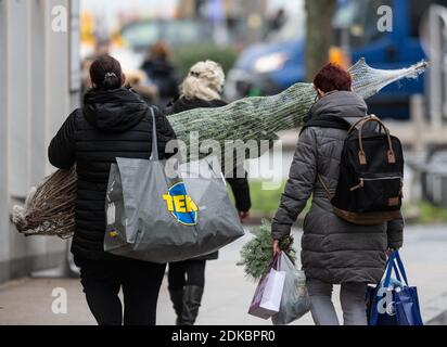 15 décembre 2020, Rhénanie-du-Nord-Westphalie, Dortmund : deux femmes marchent dans la zone piétonne avec leurs achats, y compris un arbre de Noël. A partir de demain, mercredi 16 décembre 2020 commence un verrouillage national, que les gouvernements fédéral et des États ont décidé. Photo: Bernd Thissen/dpa Banque D'Images