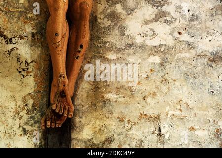 Contexte religieux. Passion, souffrent concept. Gros plan de vieux crucifix en bois avec peinture écaillée contre le mur de pierre sale grundy dans l'église. Banque D'Images