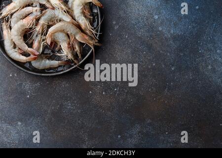 Crevettes tigrées fraîches dans un plat avec glace sur fond métallique texturé, espace de copie Banque D'Images