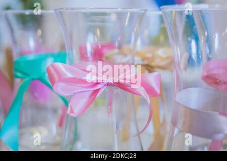 Gros plan : petits vases en verre vides pour fleurs avec noeud en tissu sur la table en magasin Banque D'Images